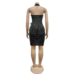 Détail de la mini robe noire moulante avec strass argentés et bordure en plumes au dos