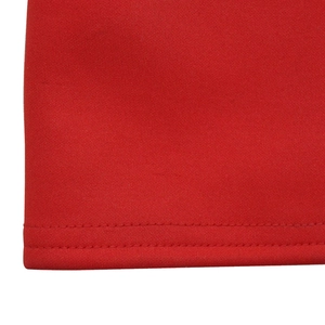 Gros plan détaillé sur la texture du tricot rouge et l'ourlet à double couture soignée