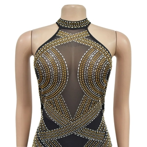 Détail d'une robe en résille noire ornée de motifs géométriques en strass dorés et argentés