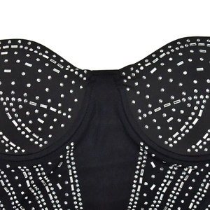 Detailed close-up of sparkling silver rhinestones on a black corset mesh dress