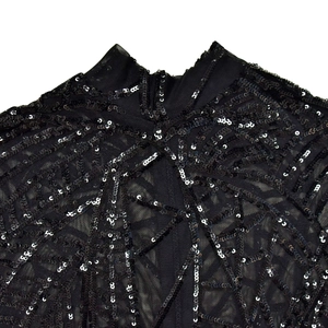 Detail of sheer black mesh collar and shoulder with intricate sequin embroidery pattern