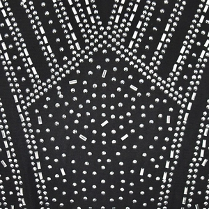 Detailed macro view of silver rhinestones in starburst pattern on black mesh dress fabric