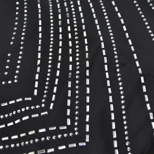 Détail de strass géométriques scintillants sur tissu noir pour une robe de soirée chic