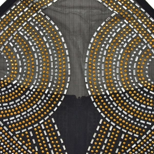 Détail du tissu en mesh noir avec motifs de strass dorés et argentés étincelants