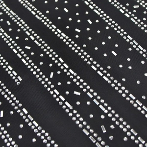 Detail of black mesh fabric featuring silver rhinestones in a linear pattern