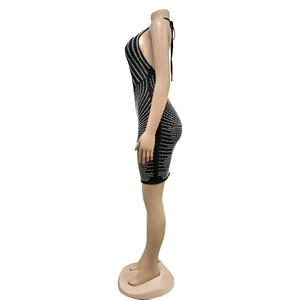 Détail d'une mini robe noire dos nu avec des strass argentés verticaux sur tissu mesh