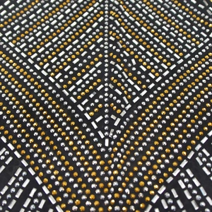 Détails macro des motifs géométriques en strass et clous dorés sur tissu en maille noire