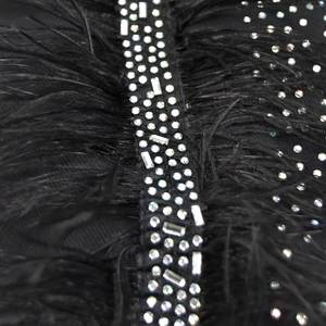Détail d'une robe noire luxueuse avec des plumes et des strass étincelants