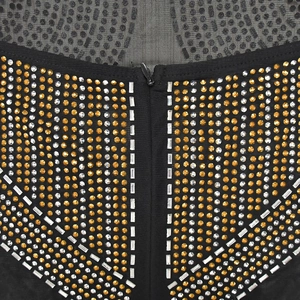 Détail de strass dorés scintillants et maille fine sur une robe de soirée noire