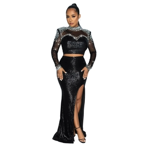Detail of black sequined two-piece dress featuring silver rhinestones and high slit skirt