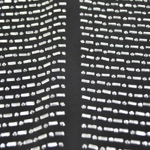 Vue rapprochée de strass argentés et cristaux sur un tissu en maille noire