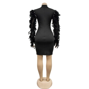 Détail d'une robe de soirée noire avec manches en plumes et broderies de perles