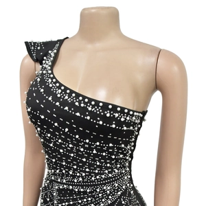 Detailed close-up of rhinestones and pearls on a black one-shoulder slim-fit dress