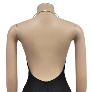 Detail view of the open-back design and golden metal neck ring on a black maxi dress