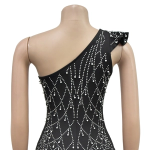 Detail of black off-shoulder dress featuring intricate pearl and rhinestone mesh patterns