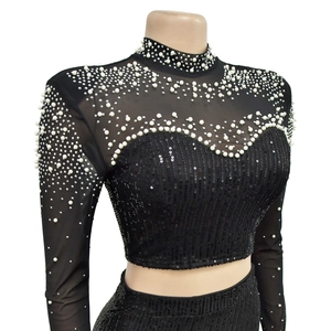 Detail of black mesh crop top with elegant white pearl neckline and shimmering sequins