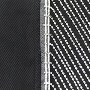 Détail de plusieurs rangées de strass argentés sur un tissu en sergé noir de qualité
