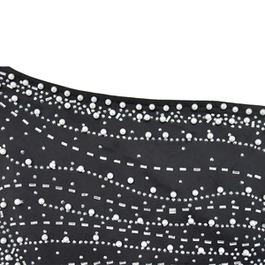 Detail of elegant black fabric with embedded pearls and sparkling rhinestones in wave pattern