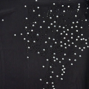 Détail du tissu en résille noire avec des strass argentés et des perles décoratives