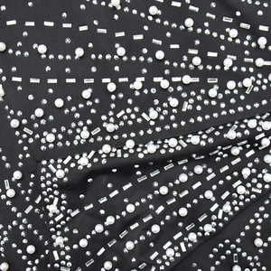 Macro detail of black evening dress fabric with rhinestones and white pearls