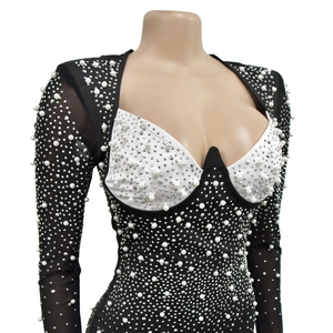 Détail des manches en maille noire et du corsage blanc orné de perles et de strass fins