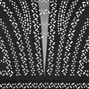 Detail of black dress featuring intricate rhinestone patterns and grey mesh neckline insert