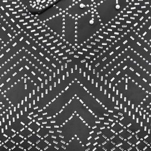 Detail of black dress fabric with sparkling rhinestones and white pearls in geometric patterns