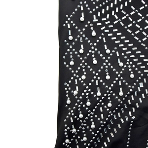 Detailed close-up of rhinestones and pearls on black fabric for elegant evening dress