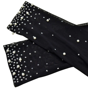 Detail of black mesh sleeves with white pearls and sparkling rhinestone embellishments