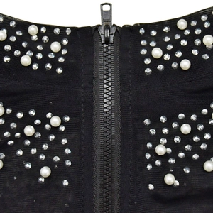 Detail of mesh fabric with white pearls, rhinestones and metal zipper on black evening dress
