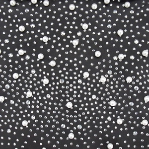 Détail de tissu en maille noire orné de strass argentés complexes et de perles blanches de luxe