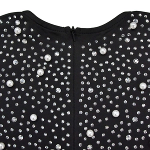 Détail du tissu en maille noire orné de strass brillants et de perles blanches élégantes