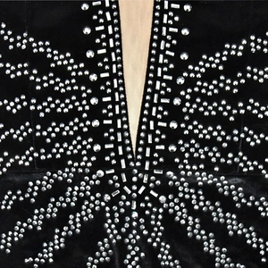 Détail d'une robe en velours noir avec décolleté en V plongeant et strass argentés brillants