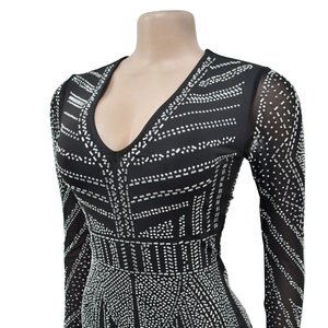 Detail of black V-neck jumpsuit featuring silver rhinestones and sheer mesh long sleeves
