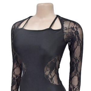 Dettaglio del patchwork in pizzo floreale su un body nero a maniche lunghe con scollo a quadrato