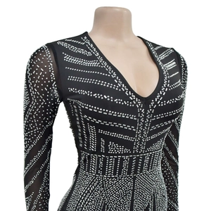 Detailed view of black V-neck jumpsuit with shimmering silver rhinestones and mesh sleeves
