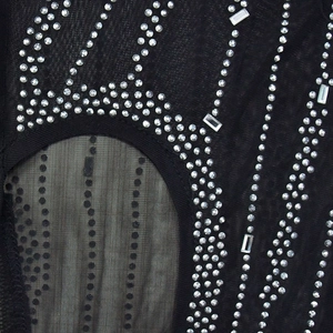 Detail von schwarzem Netzstoff mit wellenförmigem Strassmuster und silbernen Kristallen