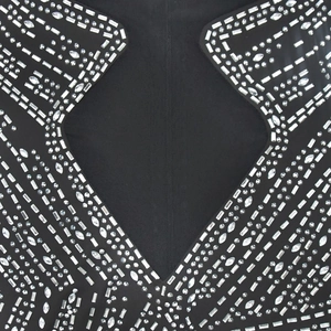 Détail de strass argentés et paillettes sur robe en maille noire avec design découpé
