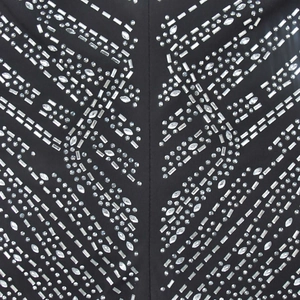 Détail de strass argentés et paillettes en motif géométrique sur une robe en maille noire
