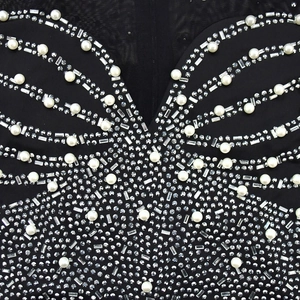 Detail of elegant black mesh jumpsuit featuring intricate pearl and rhinestone patterns