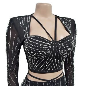 Détail d'un haut en résille noire orné de perles blanches et de strass en motifs géométriques