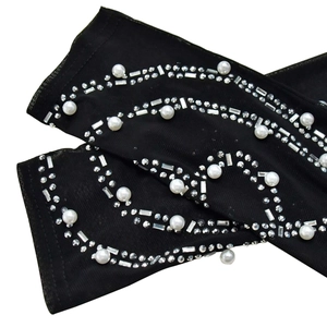 Detail of black mesh gloves with white faux pearls and sparkling rhinestone wave patterns