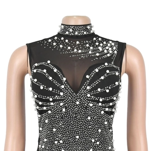 Detail view of sheer black mesh dress with intricate white pearls and sparkling rhinestones