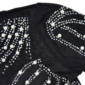 Detail of black sheer mesh dress featuring intricate white pearls and rhinestone patterns