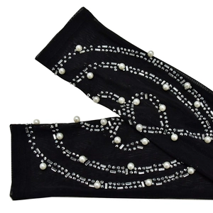 Detail of sheer black mesh sleeves featuring decorative pearls and sparkling rhinestones