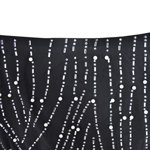 Détail d'une robe en résille noire ornée de strass brillants et de perles nacrées