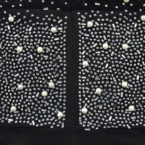 Detailed close-up of black mesh fabric with luxury rhinestones and pearls decoration