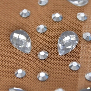 Detailed macro view of brown mesh fabric featuring sparkling teardrop and round rhinestones