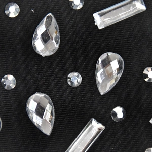 Détail macro de strass en cristal de formes variées sur tissu noir de robe chic