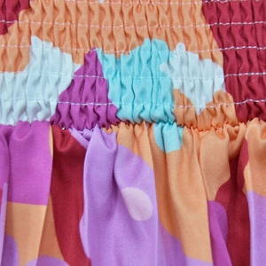 Close-up of smocking fabric detail on multi-color printed floral wide-leg jumpsuit